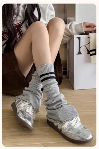Guêtres en tricot gris associées à des baskets argentées métallisées pour un look tendance.