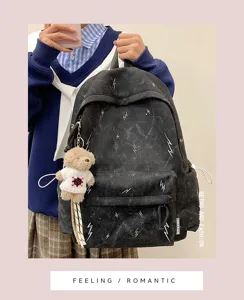 Black student backpack with white lightning patterns and plush bear charm detail