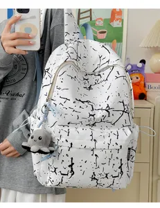 Gros plan d'un sac à dos en nylon blanc avec motif craquelé noir et charm mignon.