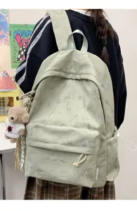 Detail view of a light green school backpack featuring lightning prints and bear charm