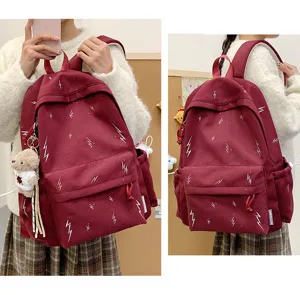Close-up view of wine red backpack featuring white lightning bolt patterns and a bear keychain