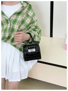 Detailed view of a mini black patent leather handbag with crocodile pattern and metal lock.