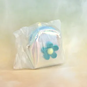 Detail view of the iridescent mini backpack coin purse featuring a cute blue flower charm.