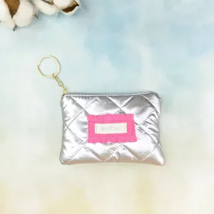 Silver quilted mini coin purse with key ring, pink ruffle detail and smooth zipper closure.