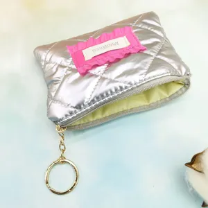 Silver quilted coin purse detail showing pink ruffled label, zipper and gold keyring.