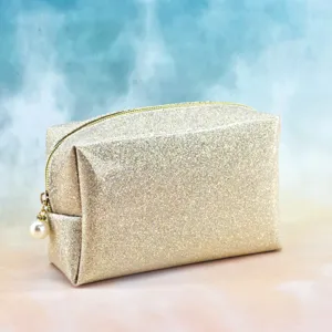 Detailed close-up of a sparkling gold cosmetic pouch with a chic pearl zipper pull charm.