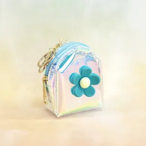 Holographic mini backpack coin purse detail, featuring a cute blue flower charm and gold keyring.