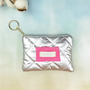 Silver quilted metallic coin purse featuring a gold keyring and cute pink ruffled fabric label.