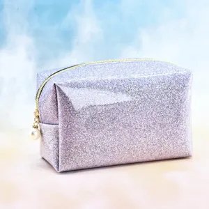 Detail shot of the glitter cosmetic bag showcasing the shiny surface, gold zipper, and pearl pull.