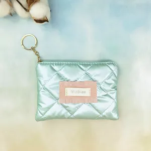 Mint green quilted coin purse detail showing soft glossy fabric, pink ruffled label, and gold hardware.