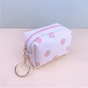Detail view of a cute white waffle strawberry coin purse with gold keychain and pink zipper.