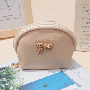 Beige semi-circular coin purse with cute bear and bow decor, compact lipstick storage bag.