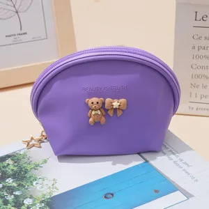 Close-up detail of cute purple shell coin purse featuring bear bow decor and zipper pull.