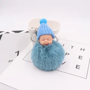 Süßer schlafender Puppen Schlüsselanhänger mit blauem Bommel und Mütze für Damentaschen.