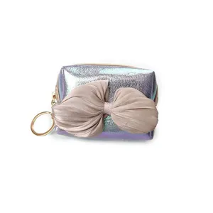 Close-up detail of the iridescent holographic coin pouch featuring a chic oversized bow zipper.