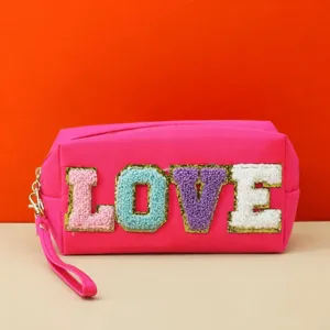 Pink cosmetic bag with plush LOVE letters, zipper and wrist strap for travel daily use.