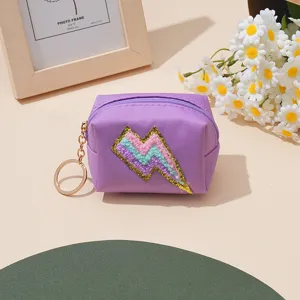 Lila Münzgeldbörse mit buntem Glitzer-Blitz-Aufnäher und Schlüsselanhänger, kleine Tasche.