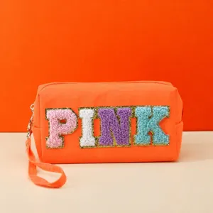 Orange cosmetic bag with stylish chenille letters, portable wrist strap and durable zipper closure.