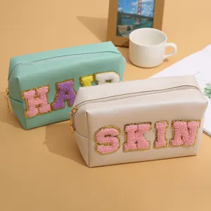 Large capacity PU leather cosmetic bag with cute plush letter patches for travel daily use.