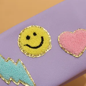 Detail shot of purple cosmetic bag with cute plush smiley heart and lightning patches.