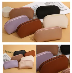 Minimalist PU leather cosmetic bag with double zipper, solid color portable shell makeup pouch.
