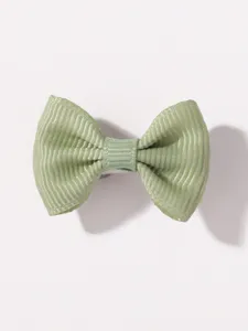 Primer plano de una pinza para el pelo con lazo verde claro y textura de tela suave para niños.