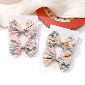 Detailed view of embroidered floral fabric bow hair clips on white display cards