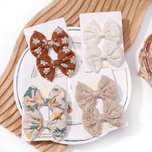 Close-up view of four sets of children's floral embroidered fabric bow hair clips