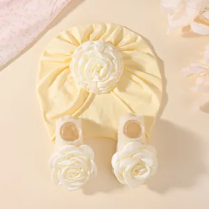 Gros plan sur l'ensemble bonnet et chaussettes pour bébé avec roses blanches élégantes, tricot.