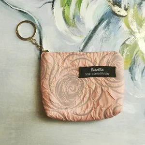 Detailed close-up of the mini pink coin purse featuring crinkled floral texture and key ring.