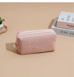 Pink corduroy cosmetic bag with gold polka dots and pearl zipper pull for travel storage