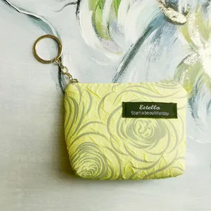 Detailed shot of yellow textured mini coin purse with keychain and zipper closure, compact design.