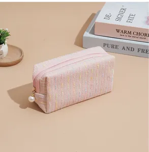 Pink tweed cosmetic bag with pearl pendant, stylish makeup pouch for travel and daily use.