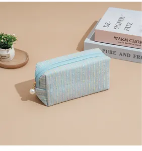 Light blue tweed makeup pouch with pearl zipper charm, portable cosmetic and storage bag for travel.