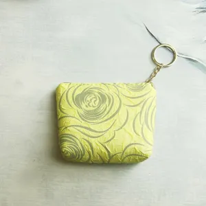 Close-up of yellow rose pattern mini zipper coin purse with gold key ring detail.