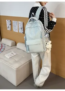 Mädchen trägt einen hellblauen Rucksack mit Sternenmuster und süßem Bären-Anhänger
