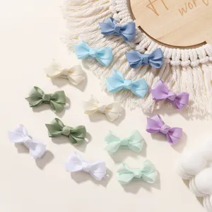 Colorful grosgrain ribbon bow hair clips for kids displayed on a macrame backdrop