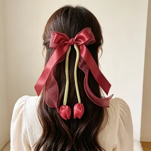 Elegant burgundy tulip bow hair clip with streamers on wavy brown hair