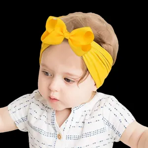 Detailed view of a baby wearing a soft yellow bow nylon headband on a black background