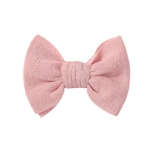 Vista dettagliata di un fermaglio per capelli a fiocco in tessuto rosa testurizzato per bambini.