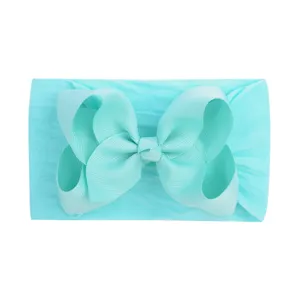 Close-up of vibrant cyan soft nylon headband with large grosgrain ribbon bow