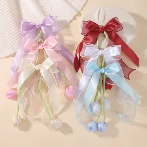 Detailed view of tulip bow hair clips with long ribbons in six assorted soft colors
