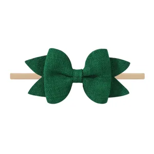 Primer plano de diadema con lazo de purpurina verde oscuro y nailon para bebés.