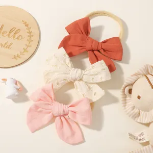 Detailopname van baby haarbanden met strikken, borduursels en linnen texturen