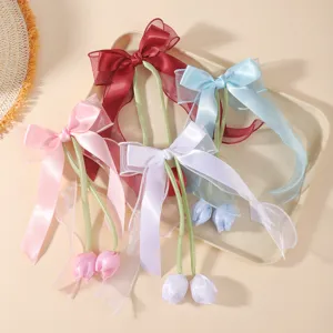 Close-up of elegant tulip bow hair clips with long satin ribbons in multiple colors