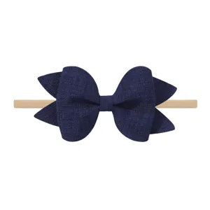 Detalle de primer plano de un lazo brillante azul marino en una diadema de nylon elástico