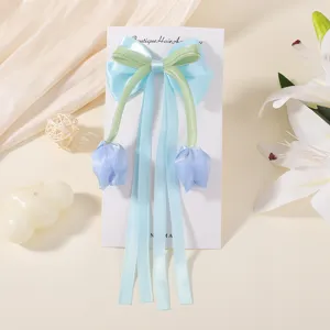 Detalle del pasador de pelo con lazo de tulipán para niñas con cintas largas azul claro.