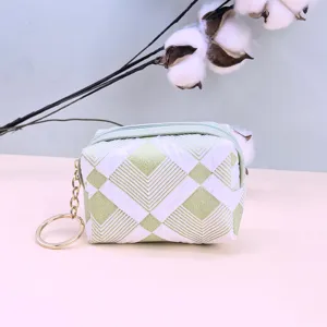 Grüner und weißer gesteppter Münzbeutel Detailansicht mit geometrischem Muster und Kette.