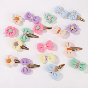 Close-up of colorful fabric flower and bow hair clips for kids on white background.