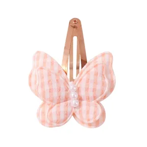 Close-up of cute pink gingham butterfly hair clip with pearl center and gold metal snap base.